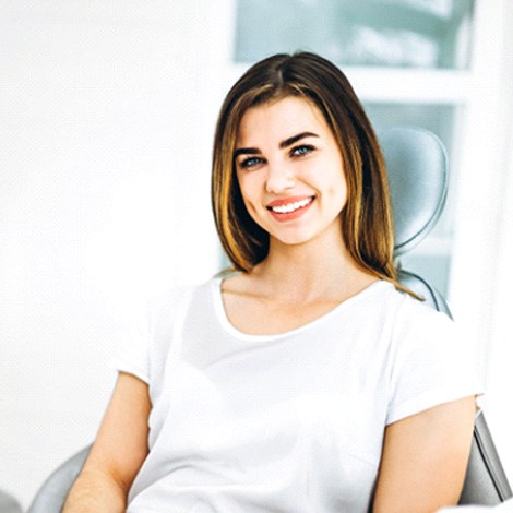 Woman in white shirt smiling in dental chair