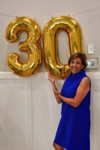Dr. Michele Jasper posting with gold balloons that say 30